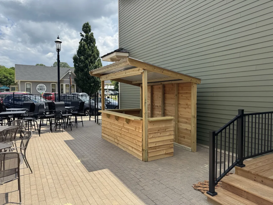 Handcrafted outdoor bar with corrugated roof and stained wood finish by Ebbesen Woodworking