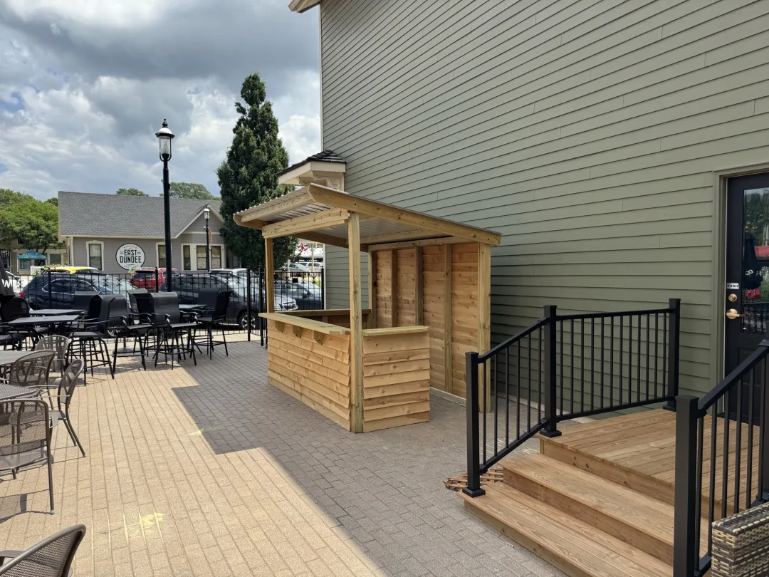 Custom backyard entertaining bar with integrated shelving and covered roofline
